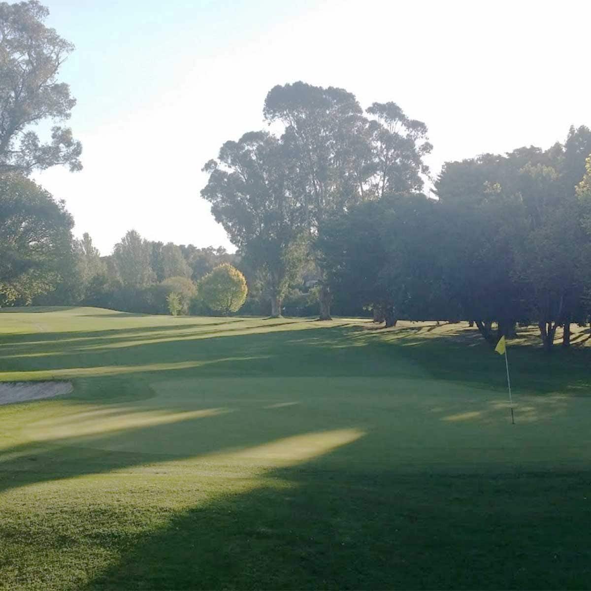 Bunkered green beneath mature trees at Queanbeyan Golf Club