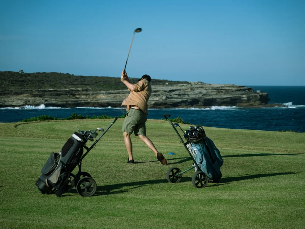 Golfer hitting a tee shot beside Malabar's rocky coastline